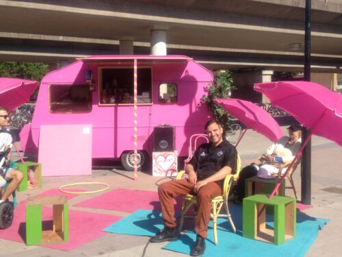 en man i en stol framför en rosa food truck i kärrtorps centrum